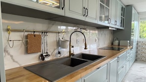 A modern kitchen with a wooden countertop, stainless steel sink, and white cabinets. - Apartament Irun (Irun)
