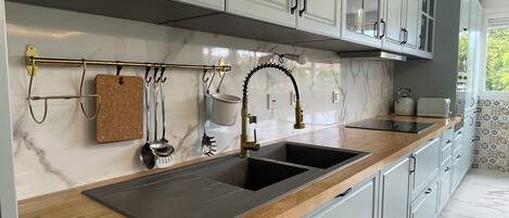 Una cocina moderna con encimera de madera, pileta de acero inoxidable y muebles blancos.