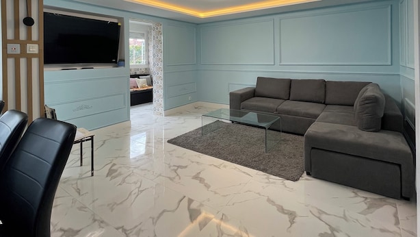 A modern living room with a sectional sofa, a glass coffee table, and a marble floor. - Apartament Irun (Irun)