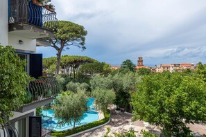 A residential building with a swimming pool, surrounded by trees and a view of a distant church tower. - Casa Bellis (Sorrento)