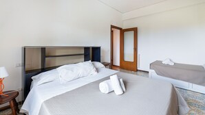 A hotel room with a large bed, a smaller bed, a desk, and a wardrobe. - Casa Bellis (Sorrento)