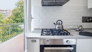 A modern kitchen with a gas stove, kettle, and a built-in oven. - Casa Bellis (Sorrento)