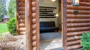 A log cabin with a dark-colored sofa inside, a ceiling fan, and a sign reading "Cedar". - Walkable Ephraim Duplex | Fall Days & Cozy Nights (Ephraim)