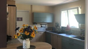Eine moderne Küche mit Essbereich, ausgestattet mit einem Holztisch, blauen Schränken und einer Vase mit gelben Blumen.