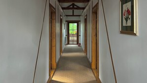 A long hallway with wooden beams on the ceiling, a framed picture on the wall, and a window at the end. - Tohanu Vechi (Zarnesti)