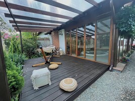 Terraza de madera con una hamaca, reposapiés y un pouf tejido.
