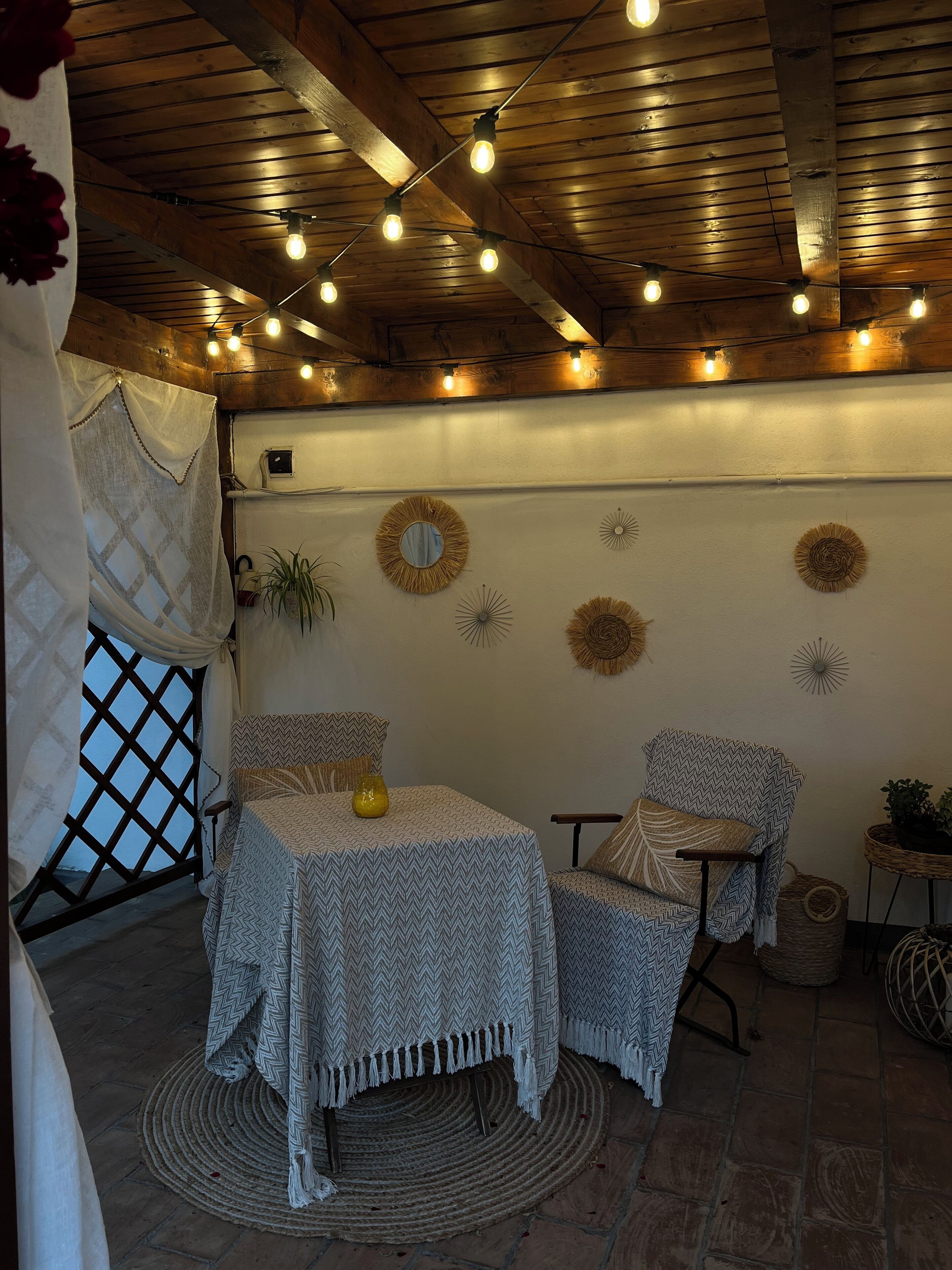 A cozy room with a wooden ceiling, a patterned table, two chairs, and decorative wall art.