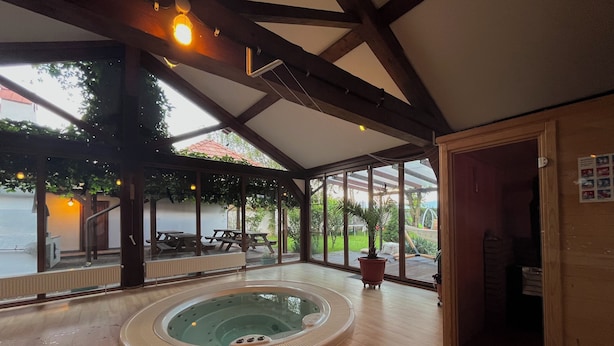 A spacious indoor area with a hot tub, wooden flooring, and large windows offering views of the outdoors. - Tohanu Vechi (Zarnesti)