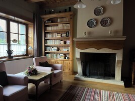 Una sala de estar acogedora con chimenea, una estantería y un ventanal con cortinas.