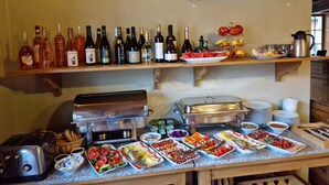 A buffet setup with various food items and wine bottles. - Tohanu Vechi (Zarnesti)