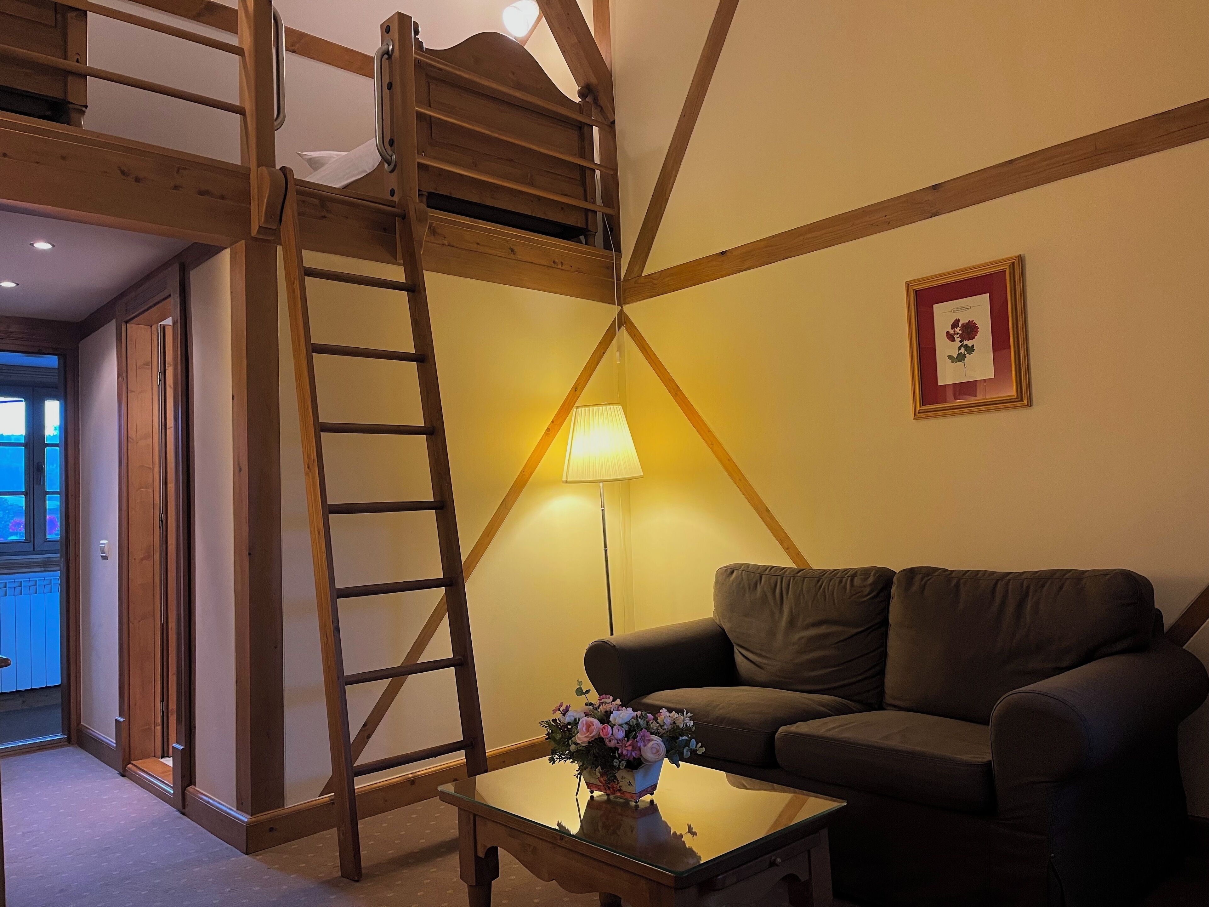 Un dormitorio tipo loft con una escalera de madera, un sofá, una lámpara y un cuadro en la pared.
