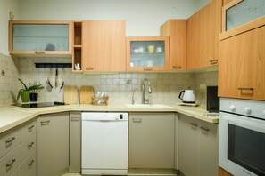 A compact kitchen with wooden cabinets, a dishwasher, a microwave, and a stove.