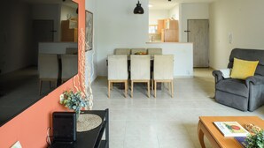 Un salon moderne comprenant un canapé, une table à manger avec des chaises, une table basse et un téléviseur.