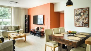Un salon comprenant un canapé, une table basse, un téléviseur et une table à manger avec des chaises.