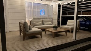 An outdoor seating area with a wooden deck, a sofa, two chairs, and a coffee table. - Castaway, Cowes beach house (Cowes)