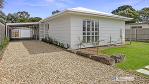 A single-story house with a covered porch, a gravel driveway, and a small garden area. - Castaway, Cowes beach house (Cowes)