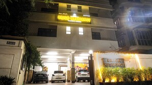 Un edificio con un cartello che riporta 'ERICA RESIDENCY' e un'area di parcheggio con auto.