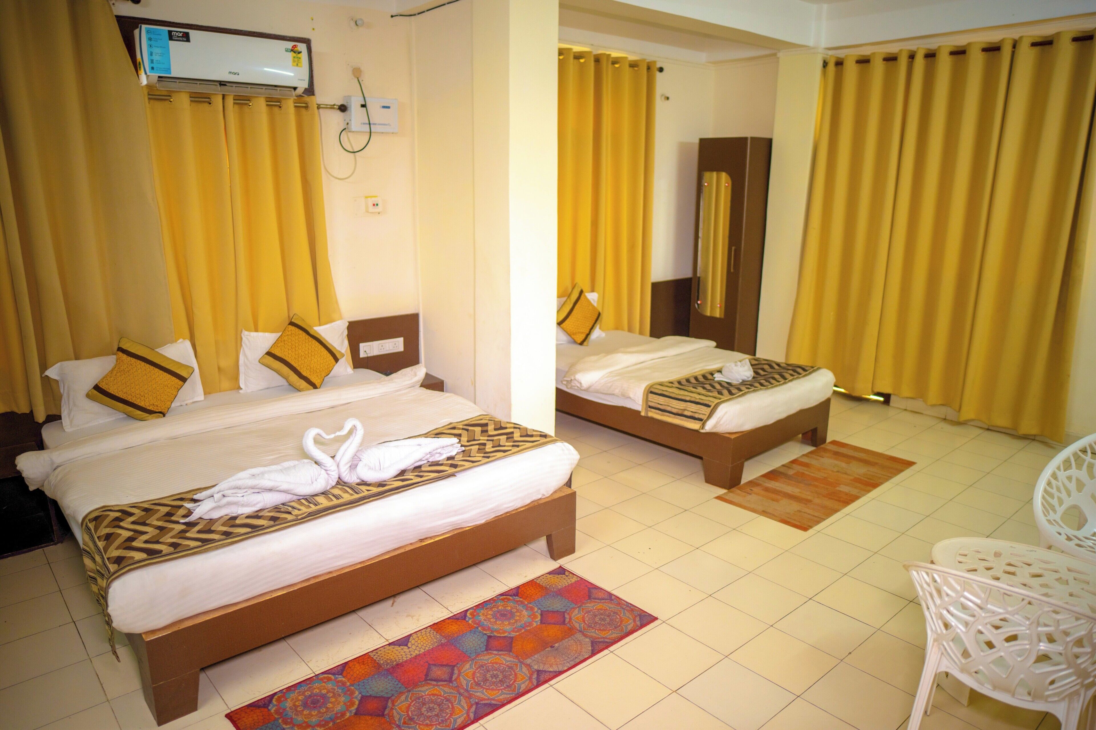 A hotel room with two beds, a bathroom, and a seating area.