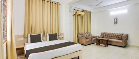 A hotel room with a bed, a sofa, a coffee table, and curtains.