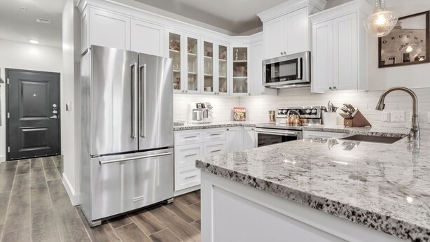 A modern kitchen with white cabinetry, stainless steel appliances, and a granite countertop. - Walk to Gruene-Guadalupe Riverfront-River Access-Stylish Texas Music Retreat (New Braunfels)
