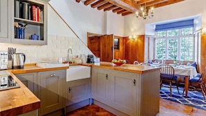 A kitchen with a wooden ceiling, a dining area with a view, and a sink. - Ostlers - beautiful former Coaching Inn with parking and late Sunday checkout. (BURFORD)