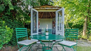 A gazebo with a glass door, a round table, and two chairs. - Ostlers - beautiful former Coaching Inn with parking and late Sunday checkout. (BURFORD)
