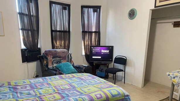 A room with a bed, a chair, a television, and a small table.