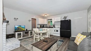 A modern living room with a dining area, kitchen, and a TV.