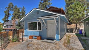 A small, single-story house with a blue exterior, a front porch, and a stone chimney.