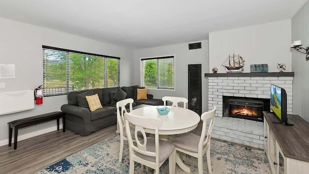 A living room with a fireplace, a sofa, a dining table with chairs, and a television.