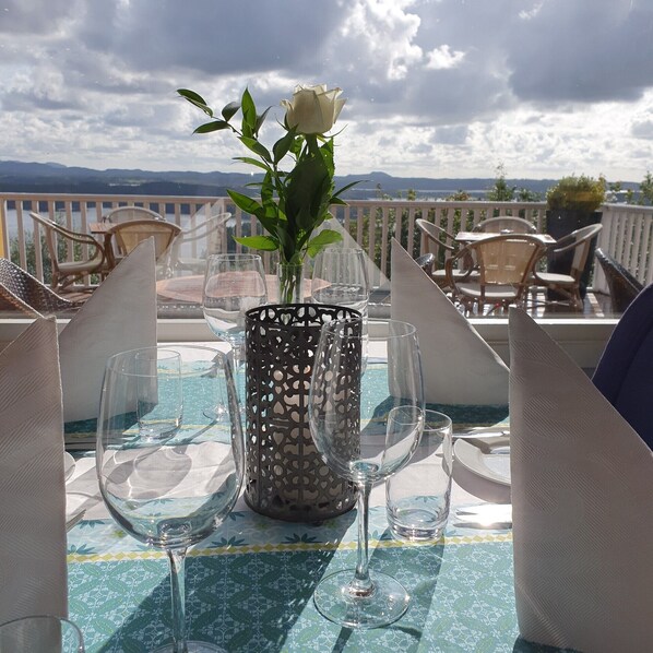 A table set for dining with a view of the mountains, a vase with a white flower, and a patterned tablecloth. - Westland Hotel (Lindås)