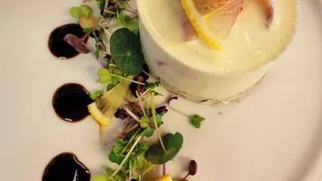 A dessert with a creamy base, lemon slices, and a red berry garnish on a white plate.