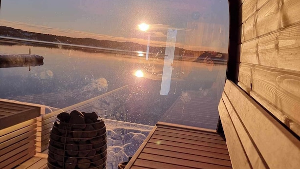 Una terraza de madera con vistas despejadas a un lago tranquilo y un atardecer.