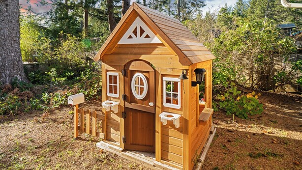 Una pequeña cabaña de madera con techo a dos aguas, una puerta principal y dos ventanas.