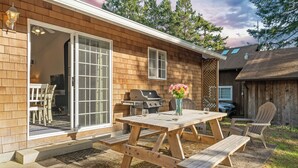 Una casa de madera con un patio, una parrilla y una mesa con sillas.