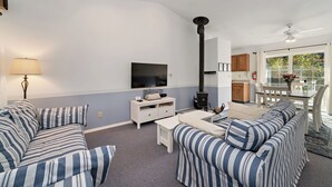 Una sala de estar con sofás a rayas, un televisor, una chimenea y una zona de comedor con una mesa y sillas.