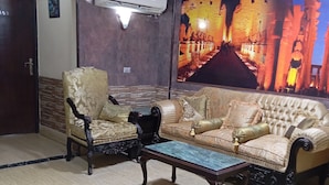 Ein Zimmer mit einer Couch, Sesseln, einem Couchtisch und einem gemusterten Teppich.