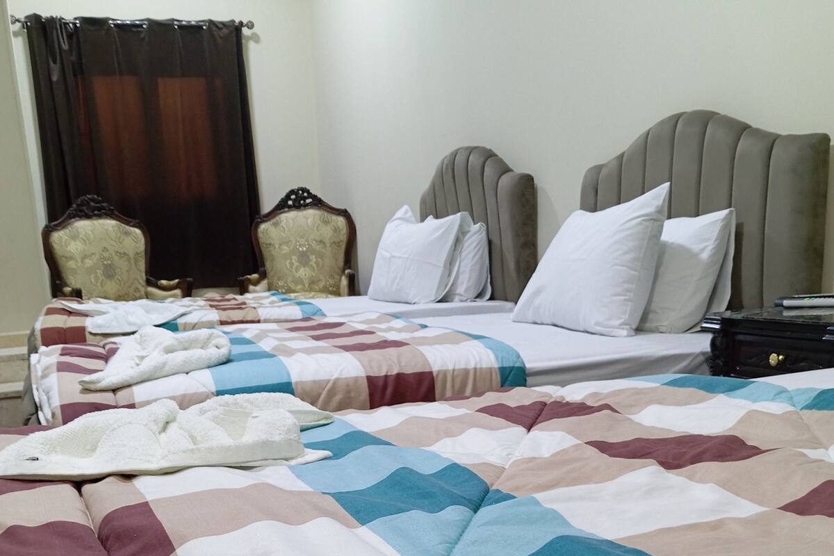 A hotel room with two beds, each with a different style of headboard and pillows.