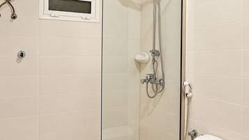 Een moderne badkamer met een douchecabine van glas, een toilet en een wandradiator.