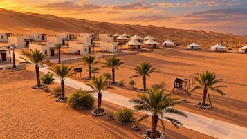 A desert resort with multiple yurts and traditional buildings, arranged in a linear fashion along a paved path.