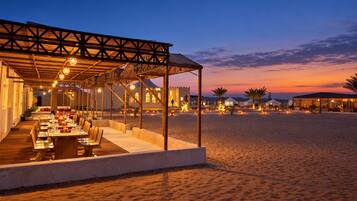 An outdoor dining area with a covered seating arrangement and a view of a building in the background.