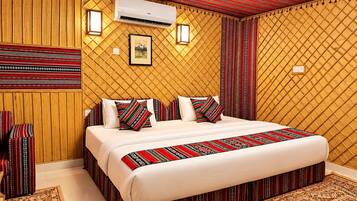 Een hotelkamer met een groot bed, kamer met patroon gordijnen en een wandairconditioner.