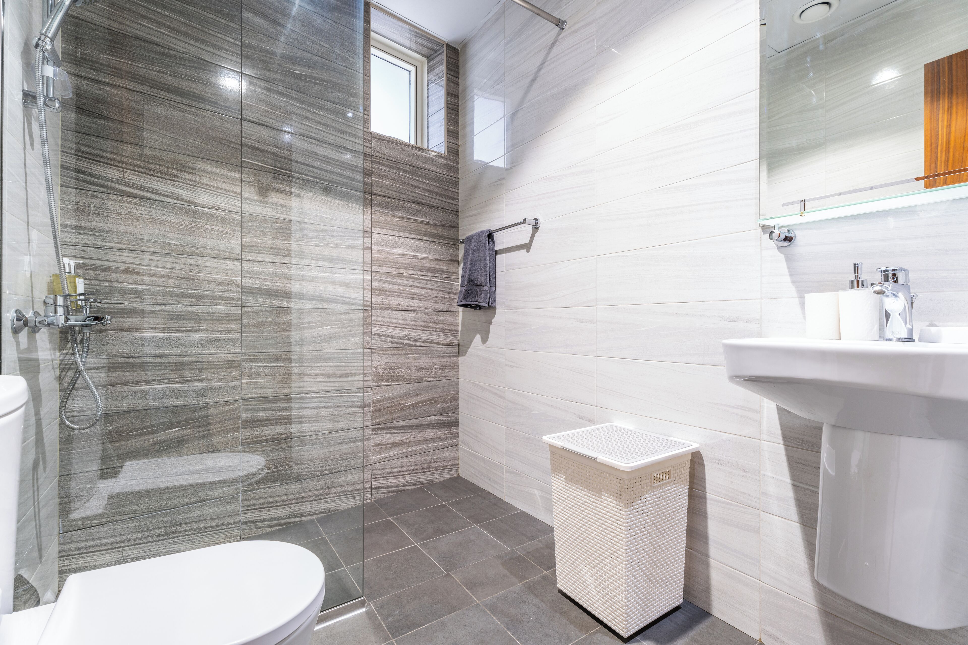 A modern bathroom with a glass-enclosed shower, a white sink, and a large mirror.