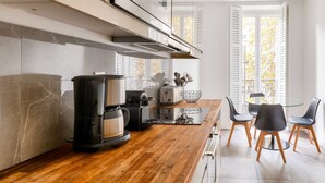 Una cocina moderna con encimera de madera, electrodomésticos integrados y un comedor con sillas y mesa.