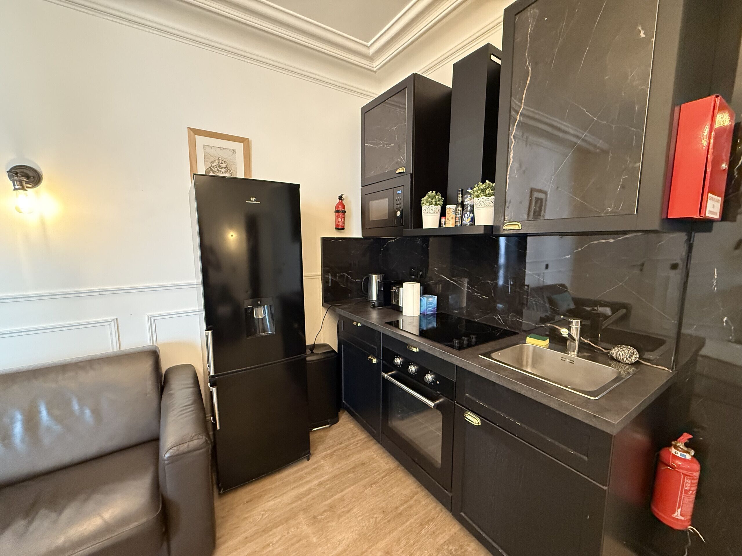 A modern kitchen with black cabinetry, a built-in oven, and a stainless steel sink.