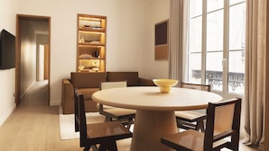 A modern living room with a round table, brown sofas, a bookshelf, and a television. - UrbanFlat 110 - Luxurious Apartment Madeleine (París)