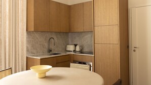 A compact kitchen with wooden cabinets, a sink, a toaster, and a bowl on the table. - UrbanFlat 110 - Luxurious Apartment Madeleine (París)