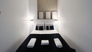A hotel room with a bed, two wall-mounted light fixtures, and three framed artworks above the bed. - Urban Flat 66 - Pretty 3 bedroom in Paris (París)