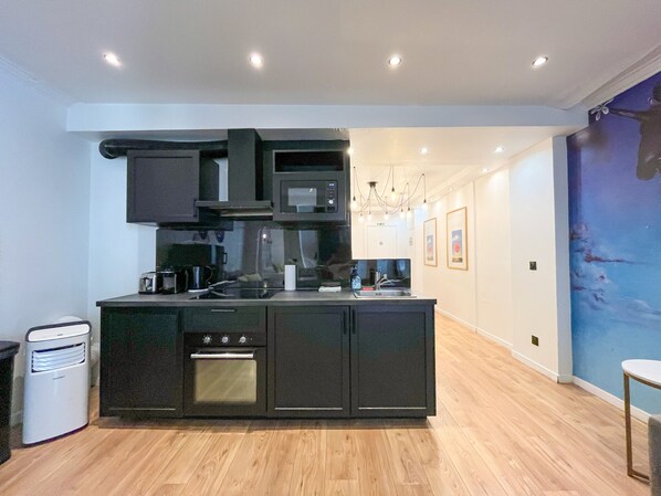 A modern kitchen with a central island, built-in oven, microwave, and sink. - 105 - Urban Haussmann Opera (París)