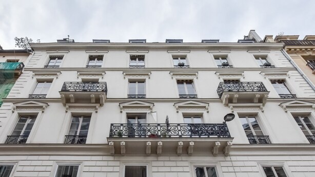 A multi-story building with white facades, multiple balconies with wrought iron railings, and a classical architectural style.